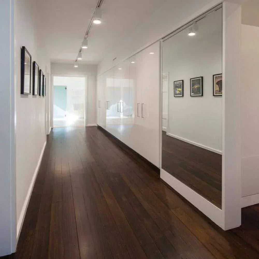 Modern hallway with LED ceiling lights, dark wood floor, white walls, and large mirrors