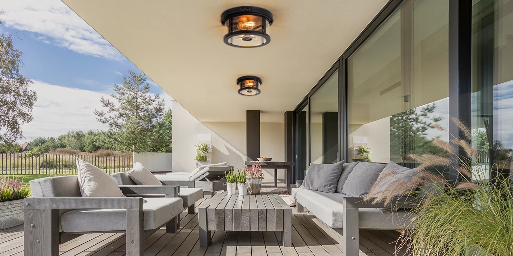 Modern outdoor patio with LED ceiling lights, gray furniture, and garden greenery