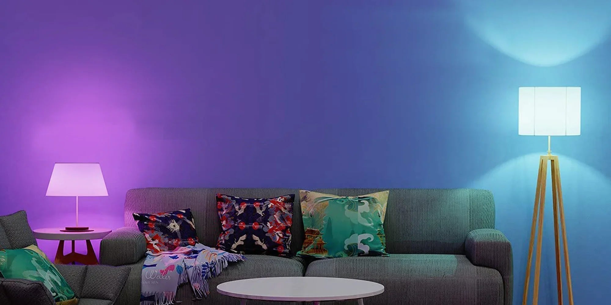 Modern living room sofa with colorful throw pillows, purple and blue LED lamps illuminating the background.